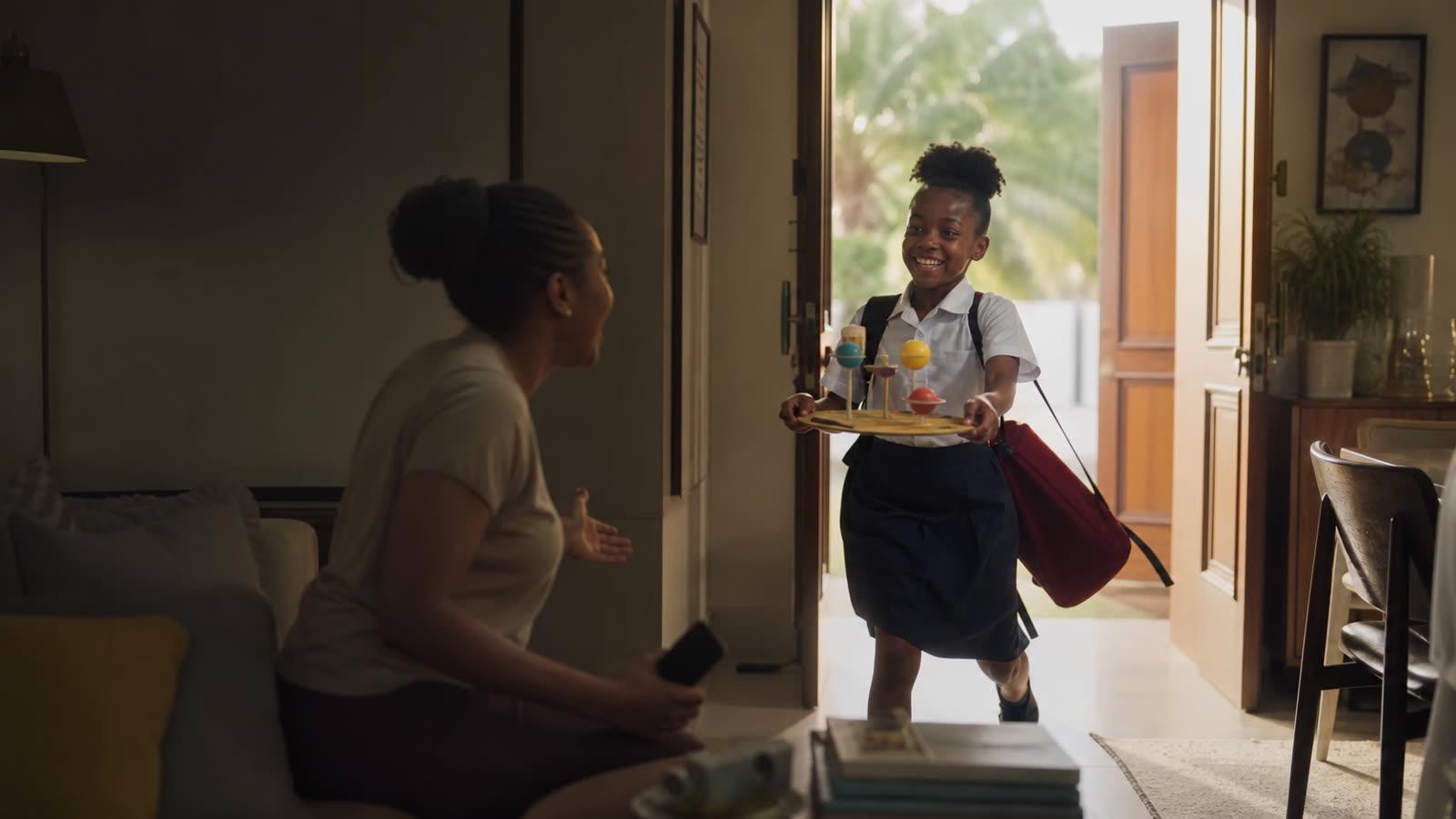 A pupil proudly showing a science project to her mother at home
